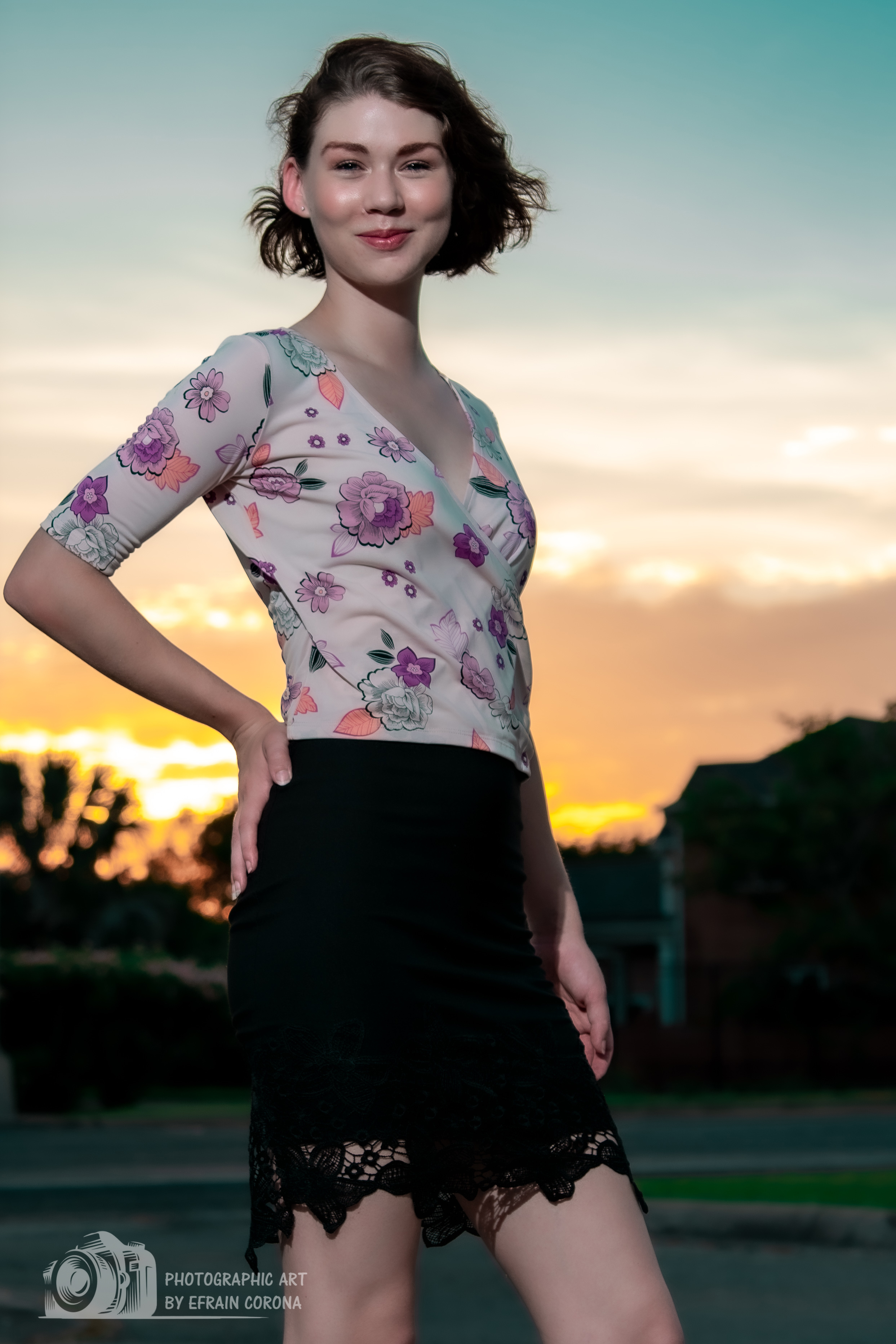 Hailey posing by the sunset in a pink floral blouse and black skirt.